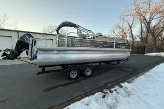 The Image of 2017 Sun Tracker Party Barge 20 DLX pontoon boat on trailer, parked near snowy area. - 1
