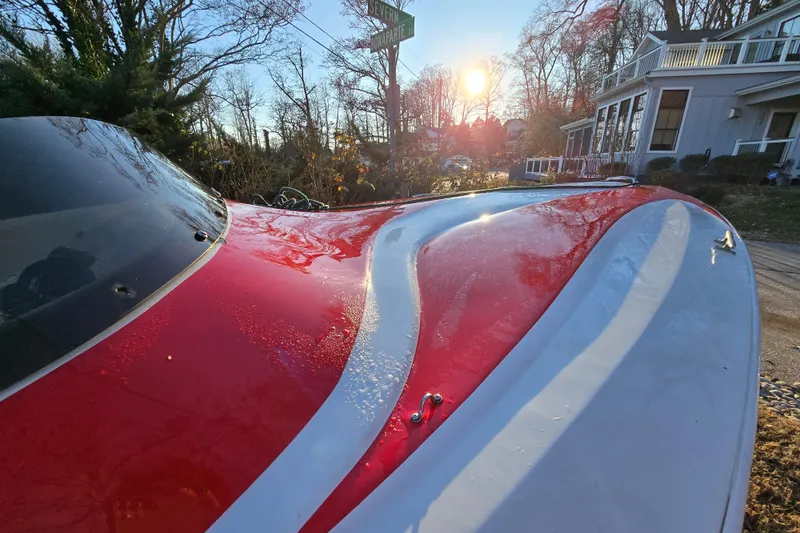 Slide: The Image of 1978 Allison Boats 20 with red and white design, parked near houses at sunset. - 2