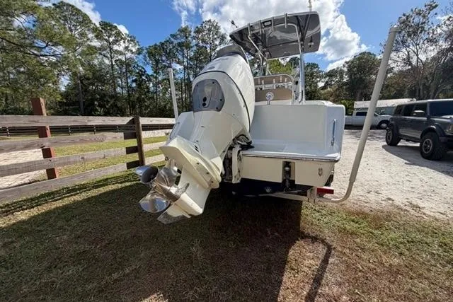 Slide: The Image of 2017 Stuart 27 boat with outboard motor, parked outdoors near trees and vehicles. - 20