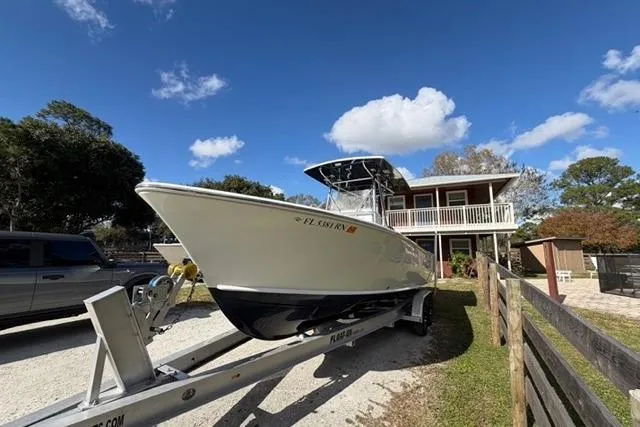 Slide: The Image of 2017 Stuart 27 boat on trailer, parked near a house under a clear blue sky. - 6