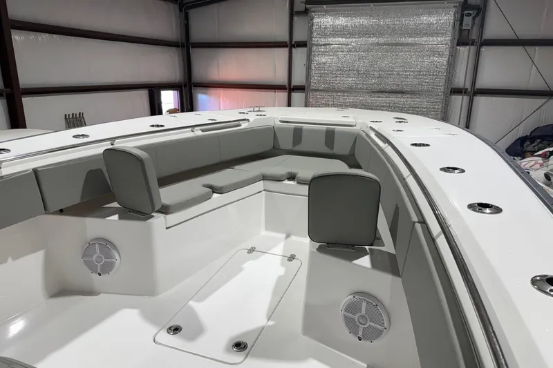 Slide: The Image of 2023 Cape Horn 34 XS boat interior with cushioned seating and speakers in a garage. - 24