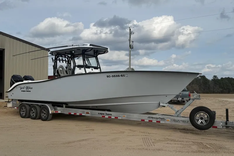 Slide: The Image of 2023 Cape Horn 34 XS boat on trailer, parked outdoors under cloudy sky. - 34
