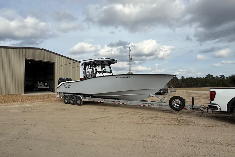 Slide: The Image of 2023 Cape Horn 34 XS boat on trailer, parked outside a large garage. - 15