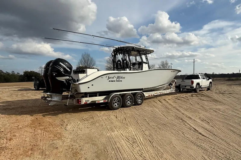 Slide: The Image of 2023 Cape Horn 34 XS boat on trailer, towed by a white truck under a cloudy sky. - 18