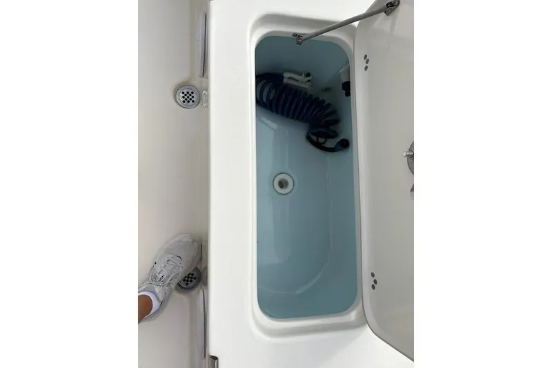 Slide: The Image of 2023 Key West 210 Bay Reef boat storage compartment with coiled hose. - 16