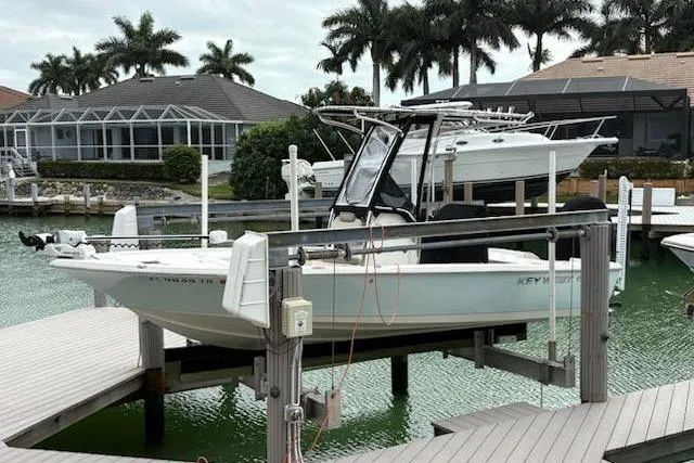 Slide: The Image of 2023 Key West 210 Bay Reef boat docked near waterfront homes and palm trees. - 2