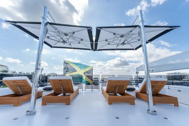 Slide: The Image of Luxurious 2006 Westport 130 Motoryacht deck with sun loungers and umbrellas under a blue sky. - 9