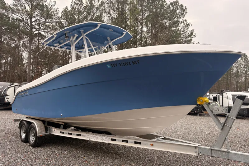 The Image of 2022 Aquasport 2500 Center Console boat on trailer, blue hull, parked outdoors. - 0