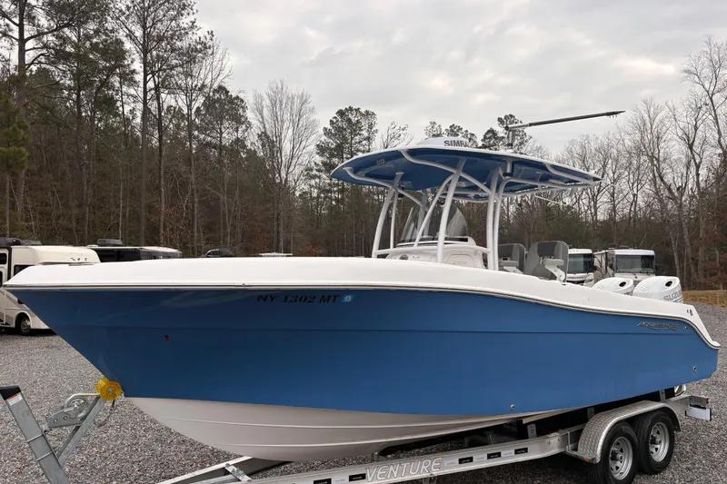The Image of 2022 Aquasport 2500 Center Console boat on trailer, blue hull, parked outdoors. - 10