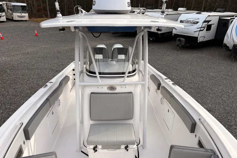 Slide: The Image of 2022 Aquasport 2500 Center Console boat with seating and storage, parked near RVs. - 18