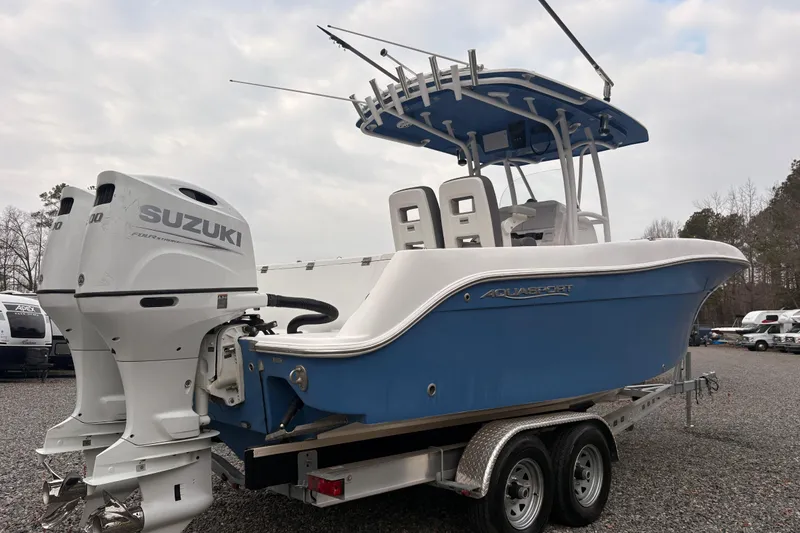 Slide: The Image of 2022 Aquasport 2500 Center Console boat with Suzuki engines on a trailer. - 2