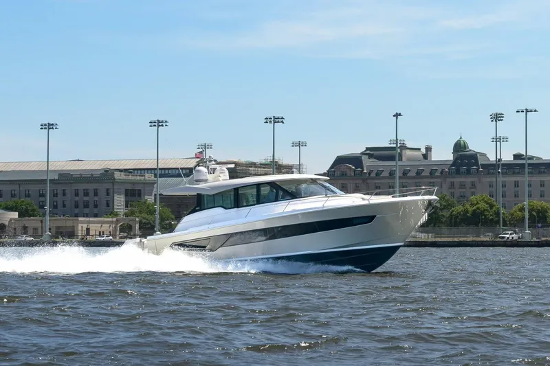 The Image of 2024 Tiara Yachts EX 60 cruising on water near urban waterfront. - 0
