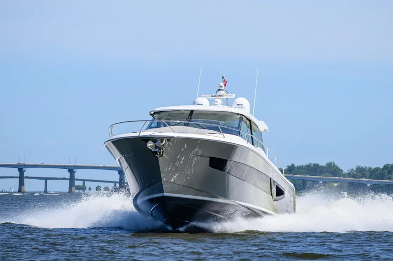Slide: The Image of 2024 Tiara Yachts EX 60 cruising on water with bridge in background. - 1