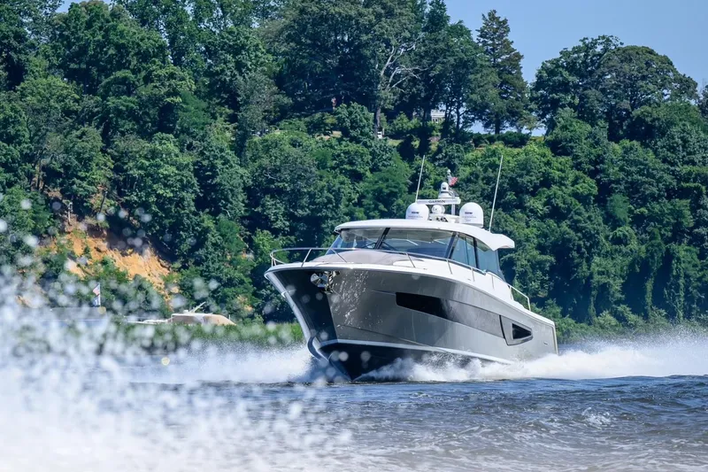 Slide: The Image of 2024 Tiara Yachts EX 60 cruising on a scenic river with lush green trees. - 2