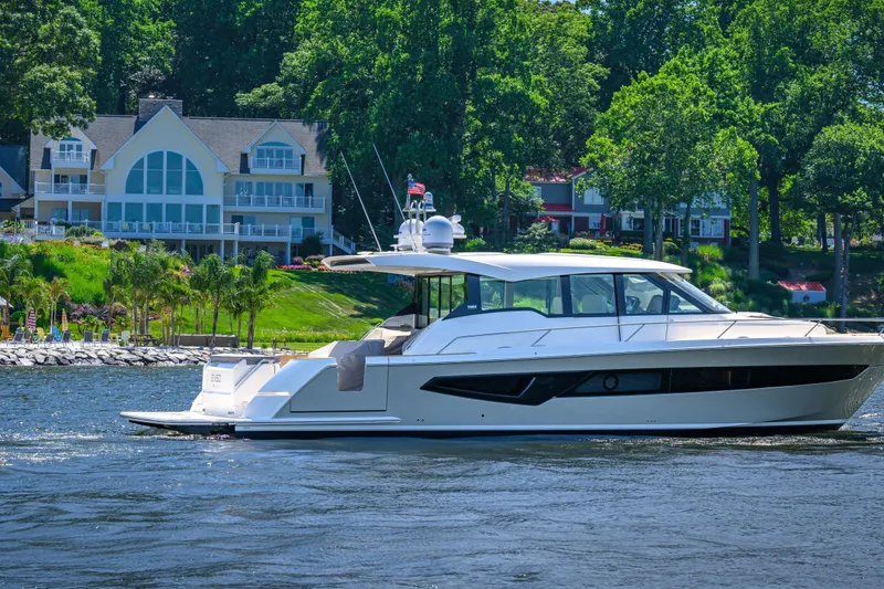 Slide: The Image of 2024 Tiara Yachts EX 60 cruising on a scenic lake near luxury homes. - 3