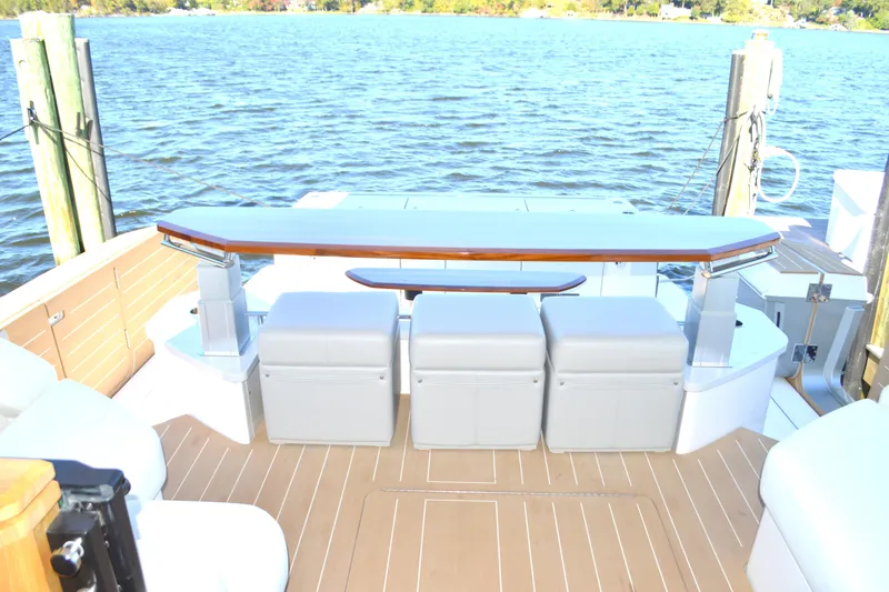 Slide: The Image of 2024 Tiara Yachts EX 60 deck with seating and table, overlooking serene water. - 31