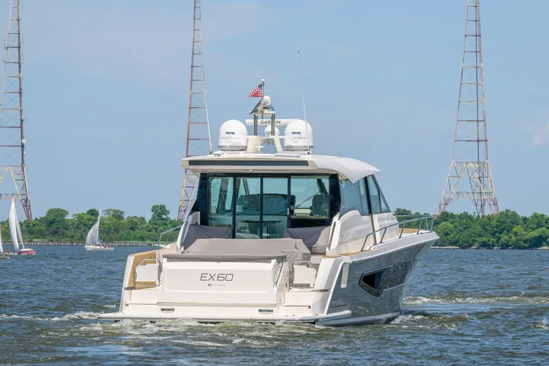 Slide: The Image of 2024 Tiara Yachts EX 60 cruising on a scenic waterway with sailboats and towers. - 4