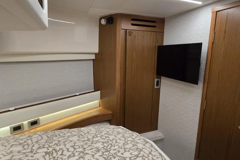 Slide: The Image of 2024 Tiara Yachts EX 60 interior cabin with wood accents and mounted TV. - 74