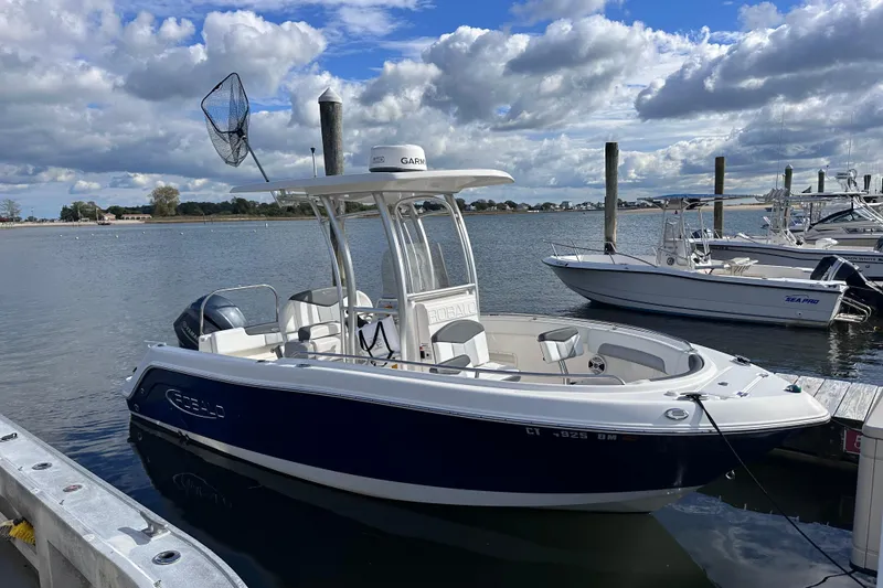 Slide: The Image of 2019 Robalo R222 Explorer boat docked by the water under a cloudy sky. - 2