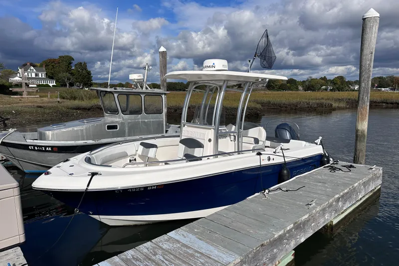 Slide: The Image of 2019 Robalo R222 Explorer boat docked by a wooden pier under cloudy skies. - 6
