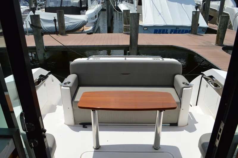 Slide: The Image of 2019 Tiara Yachts C39 Coupe cockpit with seating and wooden table, docked at marina. - 21