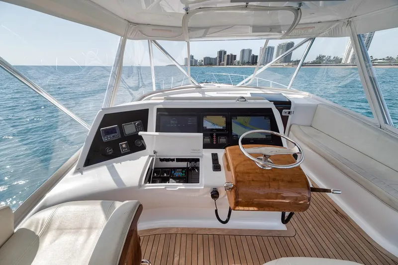 Slide: The Image of 2012 Spencer Yachts Express helm with ocean view, featuring modern navigation equipment and wooden steering wheel. - 47