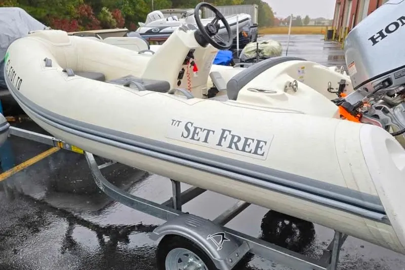 Slide: The Image of 2021 Brig Eagle 340 inflatable boat on trailer, labeled "Set Free," with Honda outboard motor. - 6