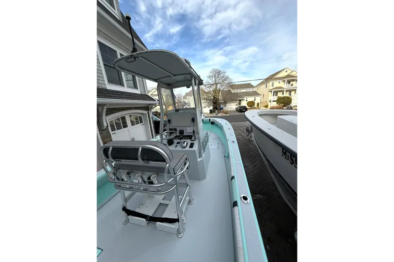 Slide: The Image of 2019 Latitude Tournament Boats 25, docked in a residential driveway, showcasing helm and seating. - 14