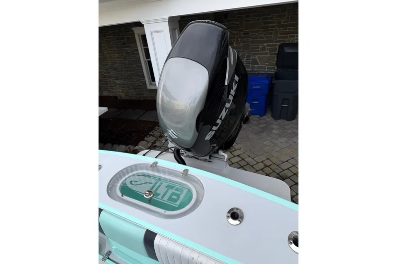 Slide: The Image of 2019 Latitude Tournament Boats 25 with Suzuki outboard motor, parked on a stone driveway. - 17