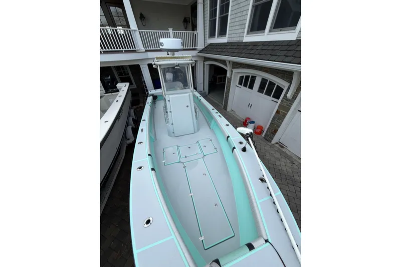 Slide: The Image of 2019 Latitude Tournament Boats 25, docked near a house, showcasing sleek design and spacious deck. - 8