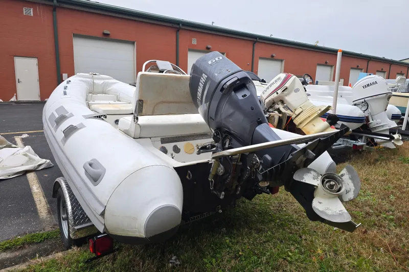 Slide: The Image of 2010 Nautica RIB 15 inflatable boat with outboard motor, parked outdoors. - 3