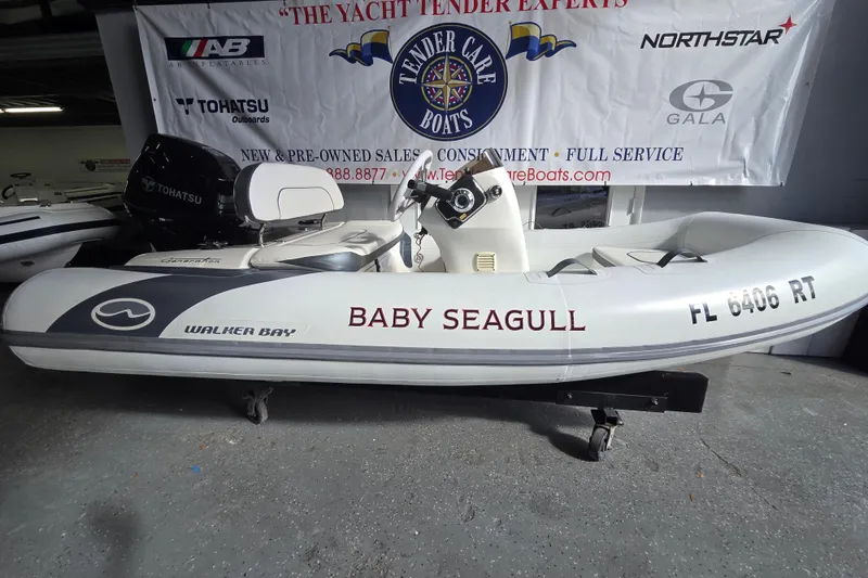Slide: The Image of 2018 Walker Bay Supertender 365 inflatable boat, labeled "Baby Seagull," displayed indoors. - 2