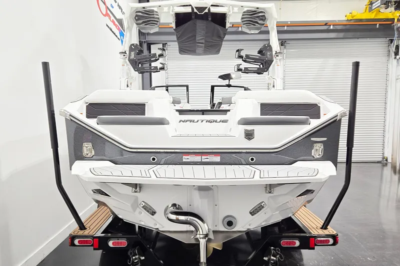 Slide: The Image of 2026 Nautique Super Air Nautique S23 boat rear view in showroom setting. - 3