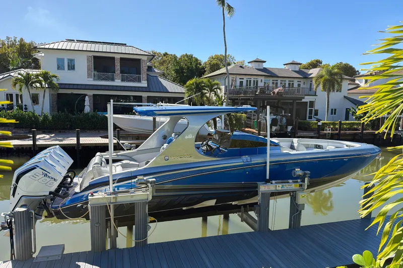 Slide: The Image of 2023 Mystic Powerboats M3800 docked by waterfront homes, featuring sleek blue design. - 3