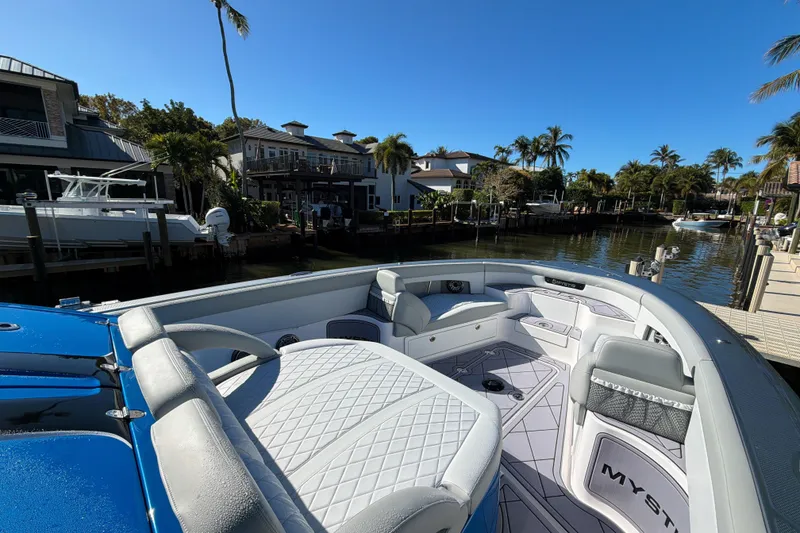 Slide: The Image of 2023 Mystic Powerboats M3800 docked in a scenic waterfront setting with palm trees. - 5