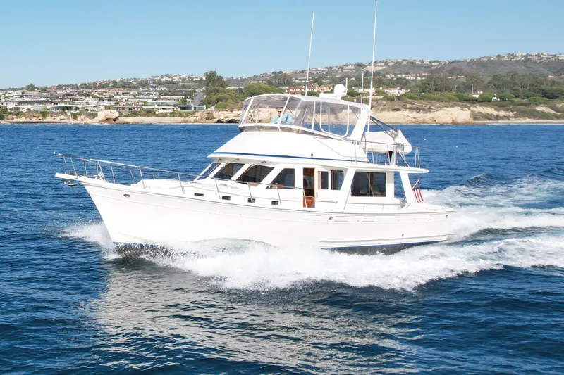 Slide: The Image of 1997 Offshore Yachts 48 Sedan cruising on blue ocean near coastal landscape. - 2