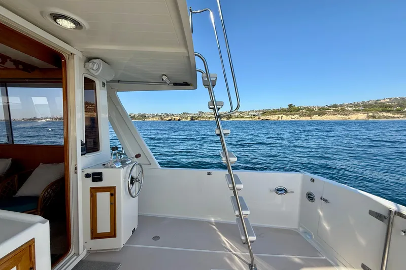 Slide: The Image of 1997 Offshore Yachts 48 Sedan, deck view with ocean and coastal landscape. - 56