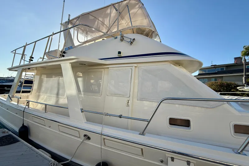 Slide: The Image of 1997 Offshore Yachts 48 Sedan, docked, showcasing sleek design and upper deck. - 86