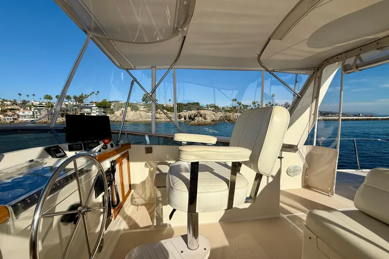 Slide: The Image of 1997 Offshore Yachts 48 Sedan interior with steering wheel, luxurious seating, and ocean view. - 74