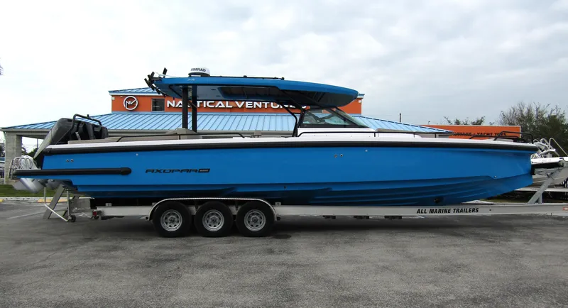 The Image of 2024 Axopar 37 Sun Top boat on trailer, vibrant blue color, side view. - 0