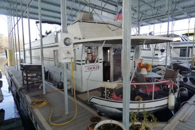 The Image of 1978 Lazy Days 14x57 houseboat docked in a covered marina, featuring outdoor seating. - 0