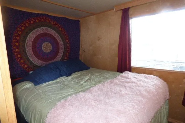 Slide: The Image of Cozy bedroom in 1978 Lazy Days 14x57, featuring a colorful tapestry and plush bedding. - 6