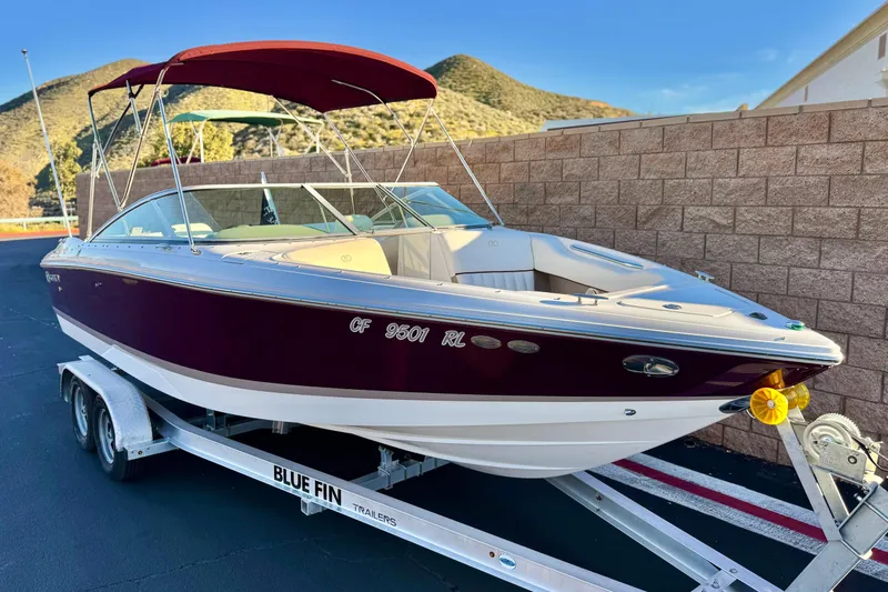 Slide: The Image of 2006 Cobalt 220 boat on trailer with red canopy, parked near brick wall. - 1