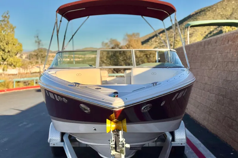 Slide: The Image of 2006 Cobalt 220 boat with red canopy on a trailer, parked outdoors. - 2