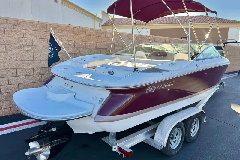 Slide: The Image of 2006 Cobalt 220 boat with maroon exterior on a trailer, featuring a canopy and flag. - 5