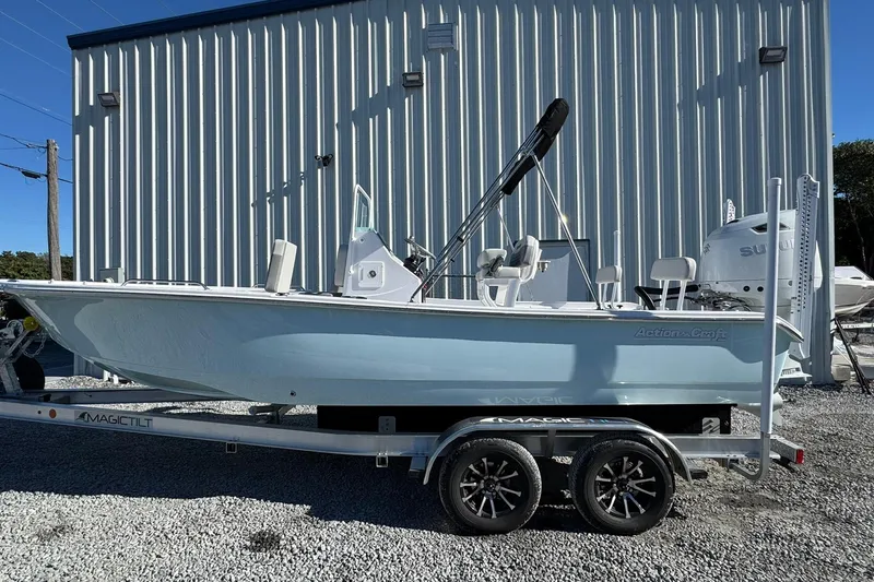 The Image of 2026 Action Craft 22 Coastal Bay boat on trailer, parked outside a metal building. - 1