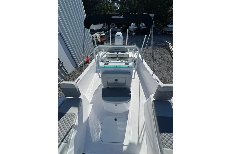 Slide: The Image of 2026 Action Craft 22 Coastal Bay boat with seating and console, parked outdoors. - 3