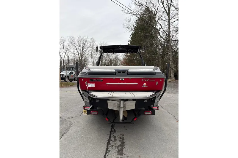 Slide: The Image of 2016 Malibu Wakesetter 25 LSV boat, red exterior, parked on a driveway. - 8