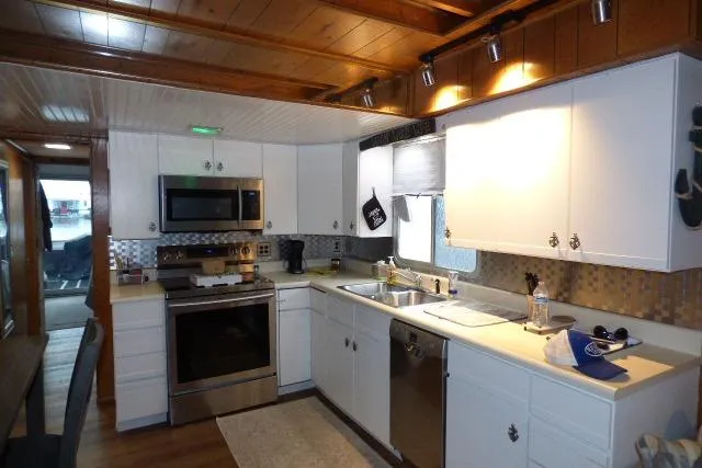 Slide: The Image of Modern kitchen interior in a 1987 Sumerset 14x64 houseboat with white cabinets and stainless steel appliances. - 4