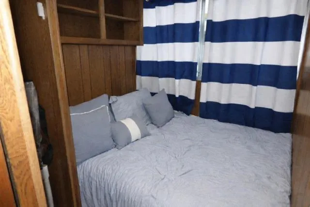 Slide: The Image of Cozy bedroom in 1987 Sumerset 14x64 houseboat with striped curtains and wooden shelves. - 6